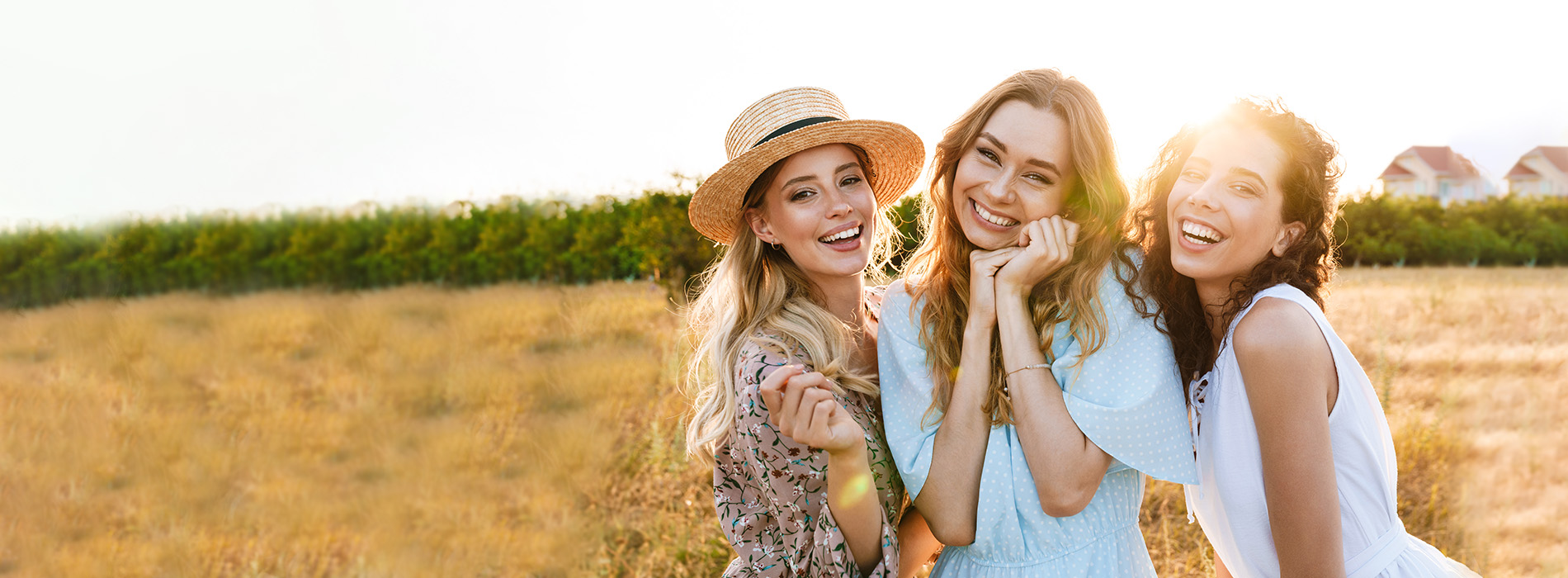 Three women posing together outdoors, smiling and enjoying a sunny day.