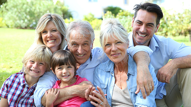 The image is a color photograph depicting a family of five, including two adults and three children, posing together outdoors.