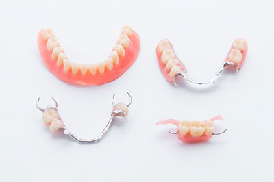 The image displays a collection of dentures with visible teeth, including both upper and lower sets.