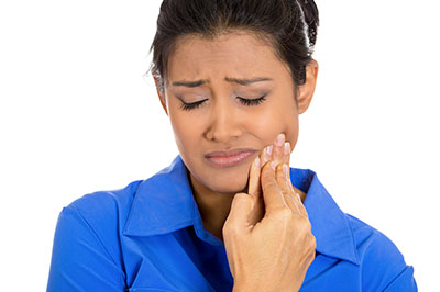 Woman with hand on face, appearing to be in pain or distress.