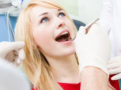 A woman in a dental chair receiving oral care, with a dental professional performing a procedure.